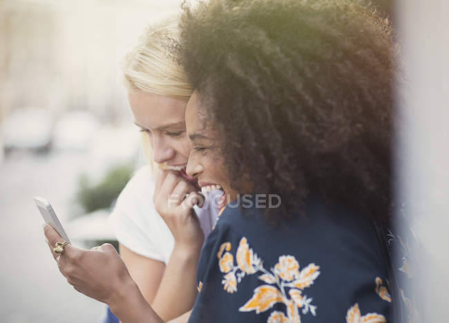 Laughing friends texting with cell phone — Stock Photo