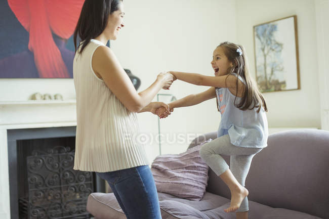 Playful mother and daughter dancing in living room — Stock Photo
