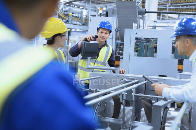 Workers talking at machinery in factory — Stock Photo