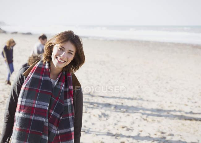 Портрет улыбающейся женщины в клетчатом шарфе на солнечном пляже — стоковое фото