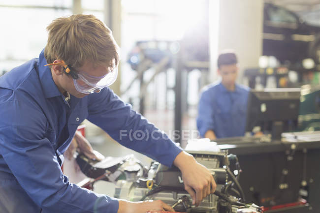 Механик, работающий над двигателем в авторемонтной мастерской — стоковое фото