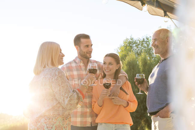 Family talking and drinking wine on sunny patio — Stock Photo