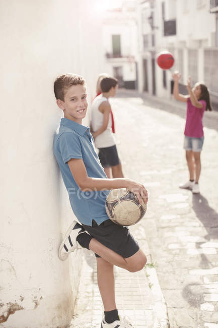 Мальчик держит футбольный мяч в переулке — стоковое фото