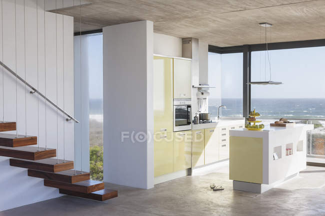 Escalera flotante y cocina moderna con vistas al océano - foto de stock