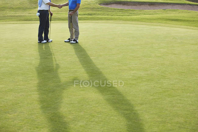 Imagem cortada de homens seniores apertando as mãos no campo de golfe — Fotografia de Stock