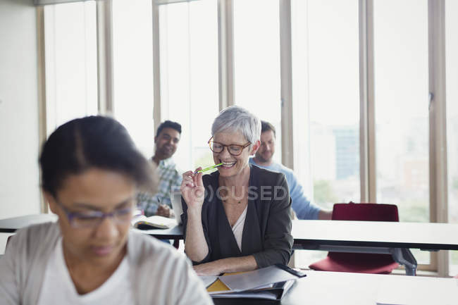 Mujer mayor sonriente estudiando en el aula de educación de adultos - foto de stock
