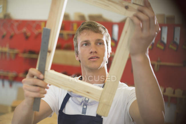 Charpentier examinant le bois en atelier — Photo de stock