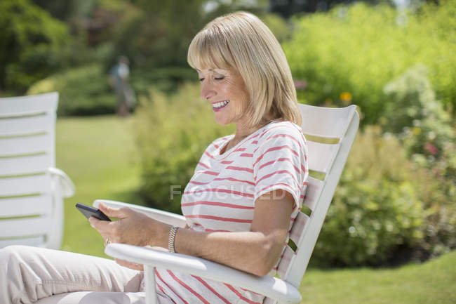 Щаслива жінка використовує мобільний телефон в саду — стокове фото