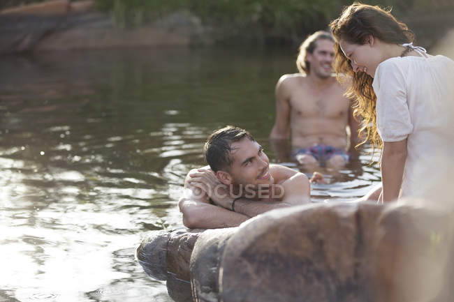 Amigos relajándose en el lago contra la roca - foto de stock