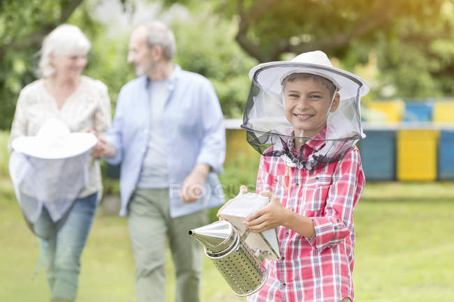 Portrait smiling boy in beekeeper hat holding smoker — Stock Photo