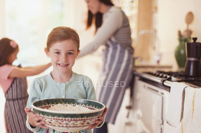 Retrato sorridente menina assar segurando tigela de farinha na cozinha — Fotografia de Stock