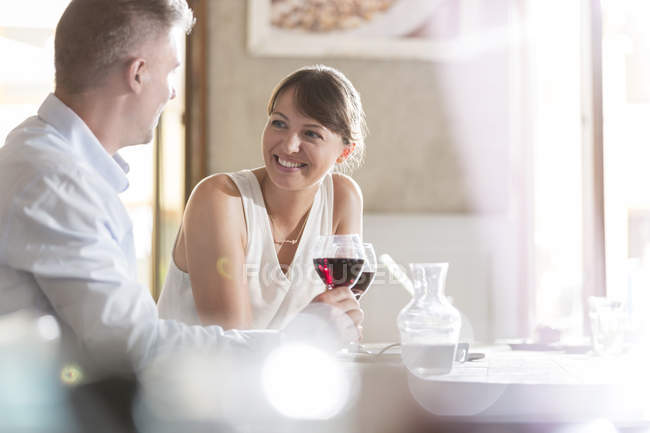 Man and woman sitting at cafe table while drinking wine — Stock Photo