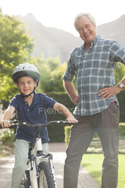 Пожилой человек учит внука кататься на велосипеде — стоковое фото