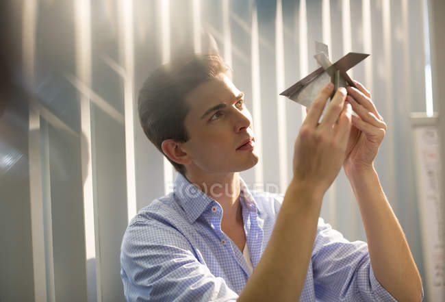 Young businessman examining model in office — Stock Photo