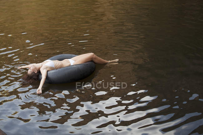 Frau schwimmt in Schlauch im Fluss — Stockfoto
