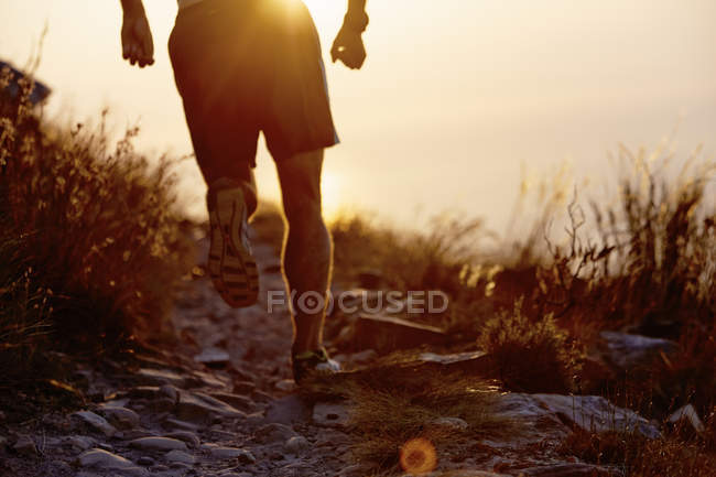 Человек, бегущий по тропе на закате — стоковое фото