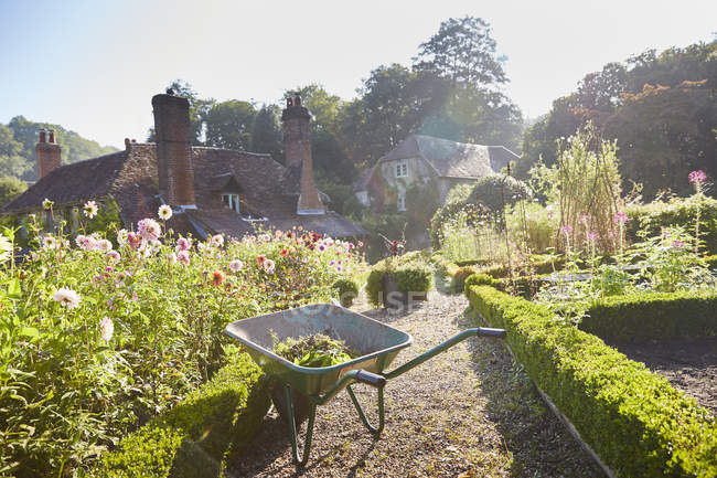Wheelbarrow in sunny formal garden — Stock Photo