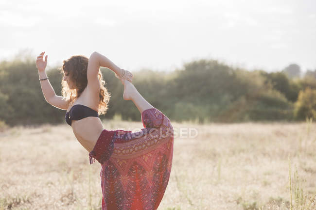 Boho-Frau in König-Tänzer-Yoga-Pose auf sonnigem Land — Stockfoto
