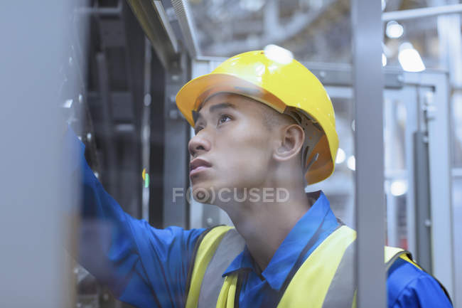Arbeiter in harter Mütze untersucht Maschinen in Fabrik — Stockfoto