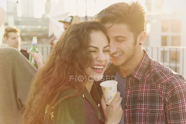 Laughing young couple hugging at rooftop party — Stock Photo