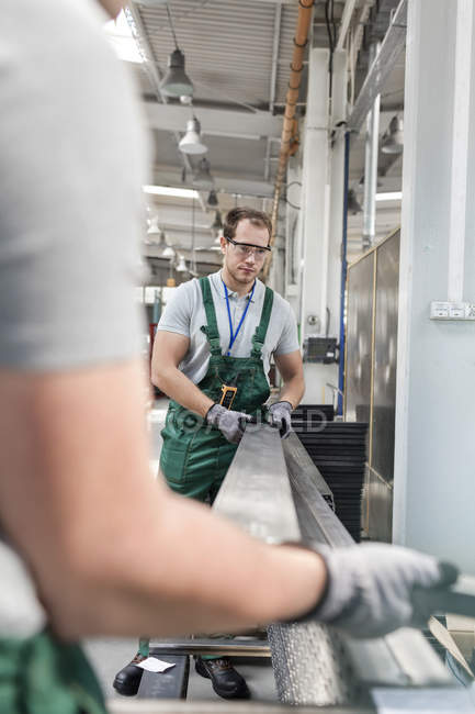 Рабочие поднимают металлические детали на заводе — стоковое фото