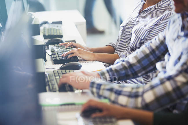 Étudiants tapant des ordinateurs dans une salle de classe d'éducation des adultes — Photo de stock