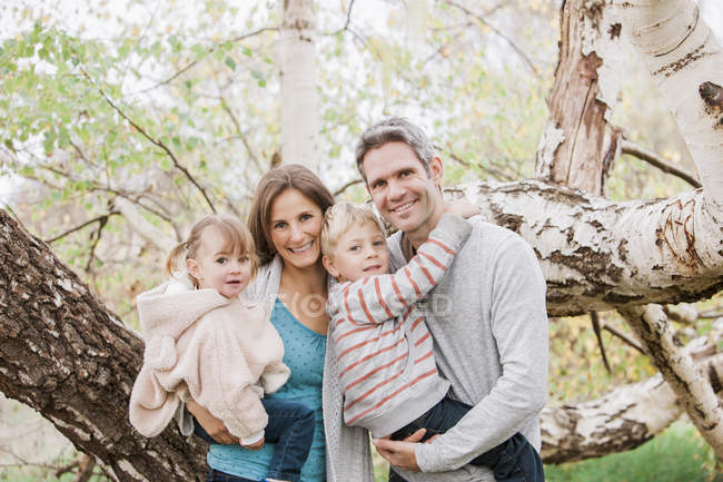 Portrait smiling family in front of tree — Stock Photo