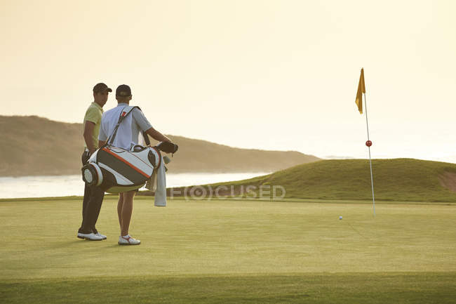 Hombres en el campo de golf con vistas al océano - foto de stock