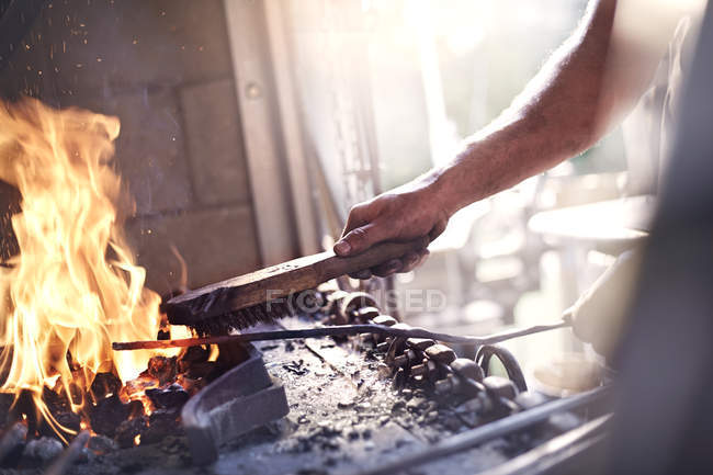 Blacksmith heating tool at fire in forge — Stock Photo