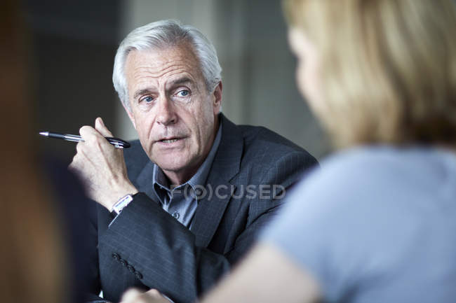 Старший бизнесмен слушает деловую женщину на встрече — стоковое фото