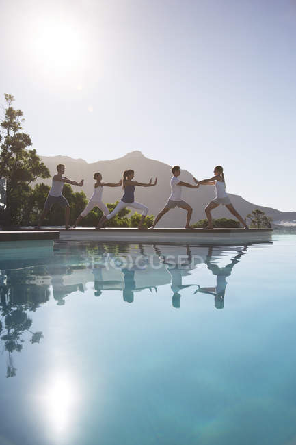 Young attractive people practicing yoga at poolside — Stock Photo