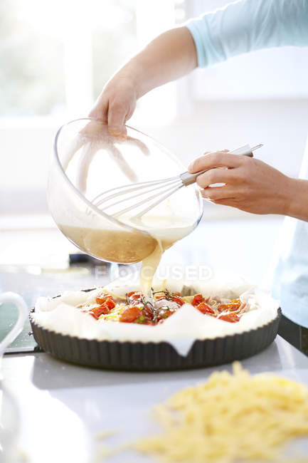 Женщина готовит пирог с помидорами на кухне — стоковое фото