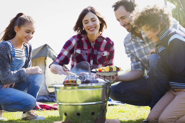 Family barbecuing at campsite grill — Stock Photo