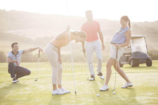 Caucasian young friends laughing on golf course — Stock Photo