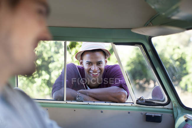Uomo sorridente appoggiato alla finestra del camper — Foto stock
