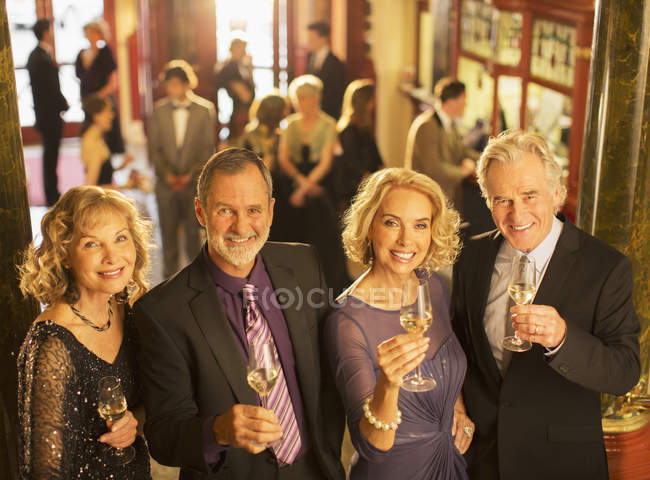 Retrato de casais felizes e bem vestidos brindando flautas de champanhe — Fotografia de Stock