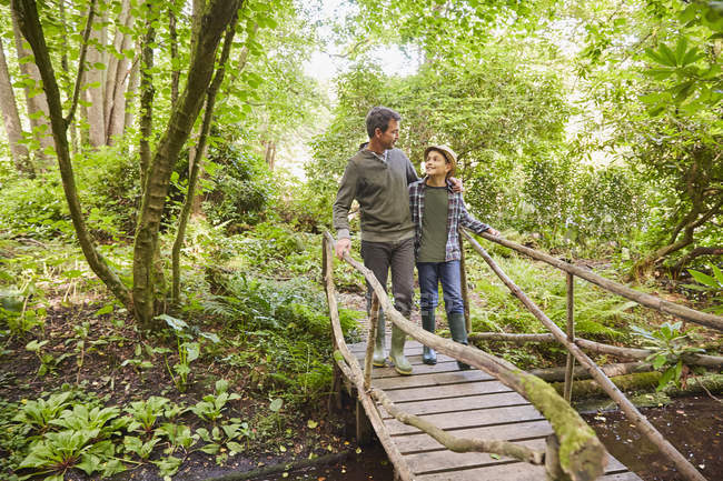 Vater und Sohn überqueren Fußgängerbrücke im Wald — Stockfoto