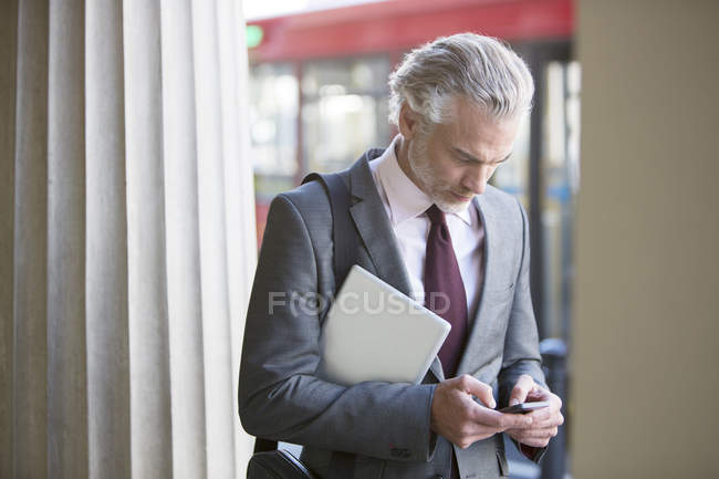 Businessman using cell phone on city street — Stock Photo