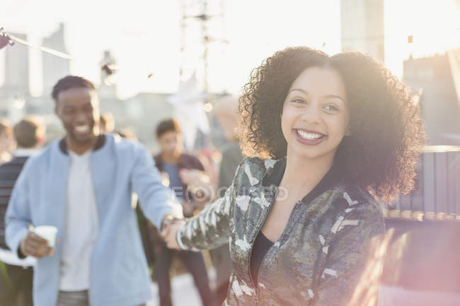 Smiling young couple holding hands at rooftop party — Stock Photo