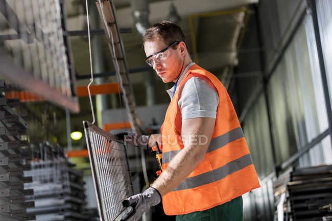 Arbeiter hält Stahlteil in Fabrik — Stockfoto