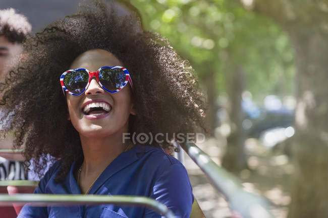 Femme enthousiaste avec afro portant des lunettes en forme de coeur — Photo de stock