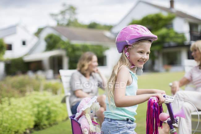Happy girl riding bicycle in backyard — Stock Photo