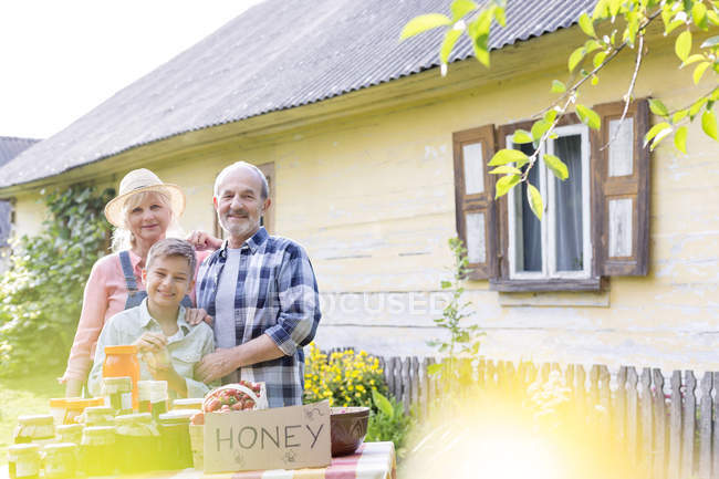 Portrait proud grandparents and grandson selling honey — Stock Photo