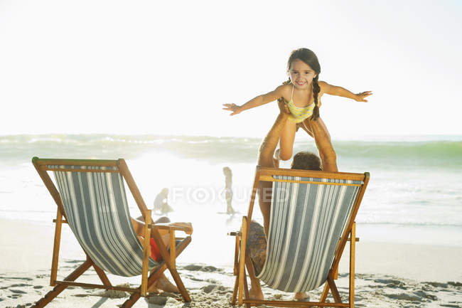 Отец поднимает дочь на пляж — стоковое фото