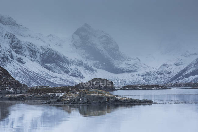 Montagne scoscese innevate sopra la baia fredda, Norvegia — Foto stock