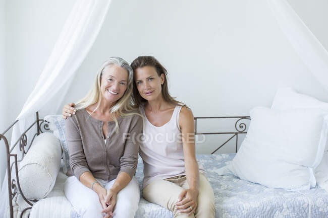 Mère et fille souriant sur lit de repos — Photo de stock