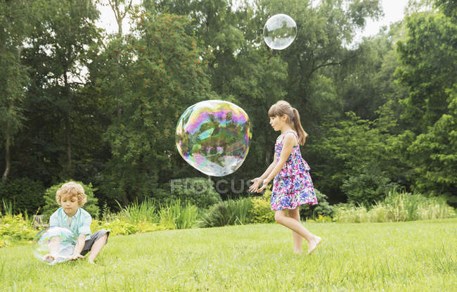 Children playing with bubbles in backyard — Stock Photo