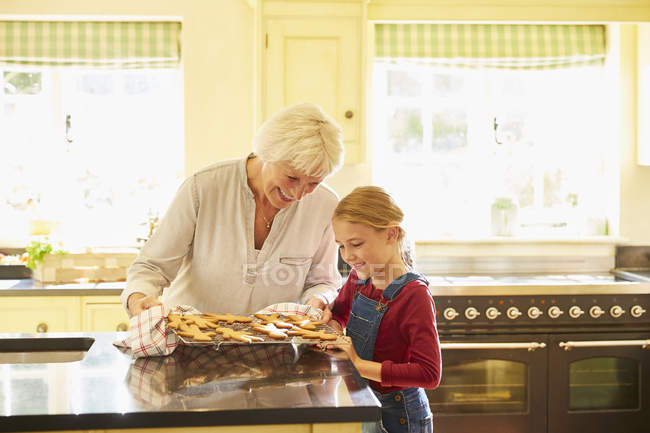 Grandmother and granddaughter baking gingerbread cookies in kitchen — Stock Photo