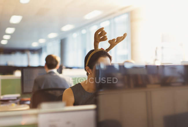 Businesswoman wearing antler headband in office — Stock Photo