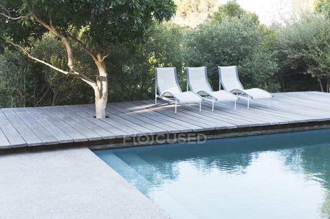 Wooden deck and lounge chairs by swimming pool — Stock Photo